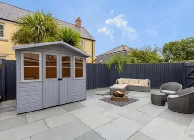 a backyard with a shed with a couch and a table at Little Sea View Duporth - 3 bed, gated beach, Nr Eden Project in Charlestown