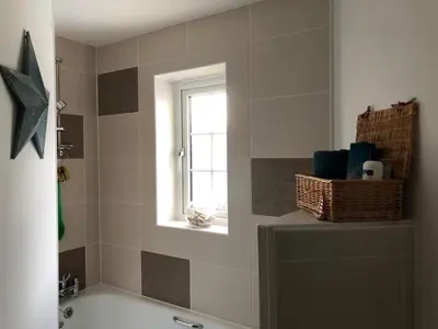 a bathroom with a bath tub and a window at Little Sea View Duporth - 3 bed, gated beach, Nr Eden Project in Charlestown