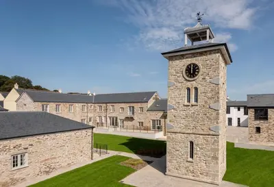 a clock tower in front of a building at Little Sea View Duporth - 3 bed, gated beach, Nr Eden Project in Charlestown