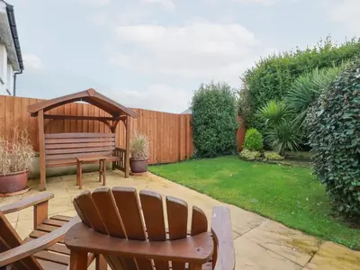a garden with a wooden bench and a gazebo at Blissful Ocean Breeze in Perranporth