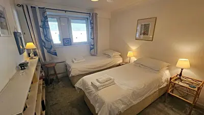 two beds in a small room with a window at Little Egret in Saint Mawes