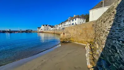 a stone wall next to a body of water at Little Egret in Saint Mawes