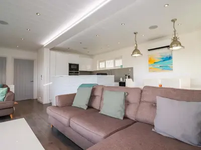 a living room with a couch and a kitchen at South Crofty - The Residence in Redruth