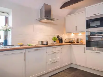 a white kitchen with white cabinets and appliances at The Granary, Engollan in Wadebridge