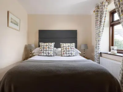 a bedroom with a large bed with a black headboard at The Granary, Engollan in Wadebridge