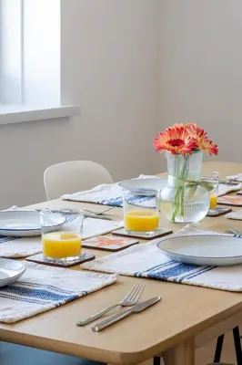 a wooden table with plates and glasses of orange juice at Stunning sea-view apartment close to Fistral Beach in Crantock