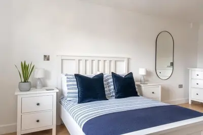a white bedroom with a bed with blue pillows at Stunning sea-view apartment close to Fistral Beach in Crantock