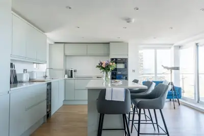 a kitchen with white cabinets and a table with chairs at Stunning sea-view apartment close to Fistral Beach in Crantock