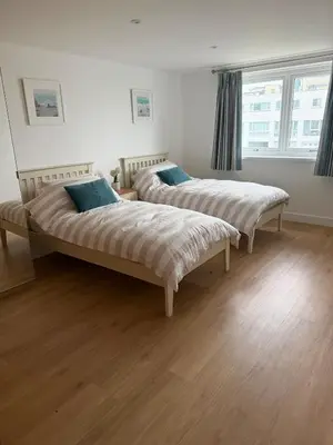 two beds in a room with wooden floors at Stunning sea-view apartment close to Fistral Beach in Crantock