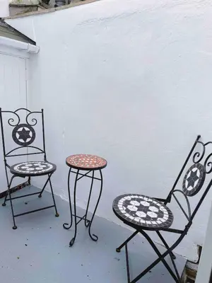 two chairs and a table next to a wall at Seaside Cottage Ideal for Families and Surfers in St Ives