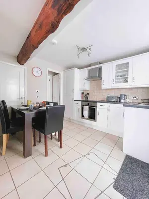 a kitchen with white cabinets and a table with chairs at Seaside Cottage Ideal for Families and Surfers in St Ives