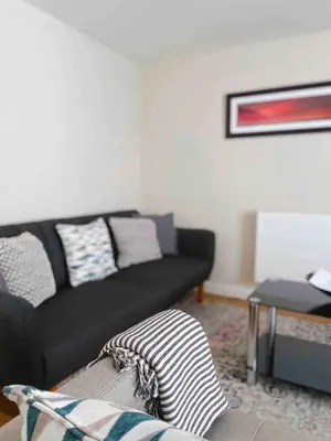 a living room with a black couch and a table at Seaside Cottage Ideal for Families and Surfers in St Ives