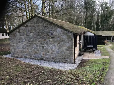 a small stone building with a gate in a yard at The Artist's Cottage in Uny Lelant