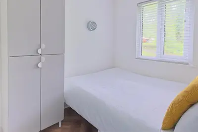 a white bedroom with a bed and a window at The Artist's Cottage in Uny Lelant