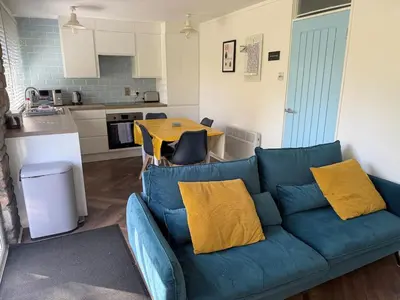 a living room with a blue couch and a kitchen at The Artist's Cottage in Uny Lelant