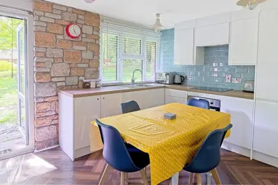 a kitchen with a table with blue chairs and a counter at The Artist's Cottage in Uny Lelant