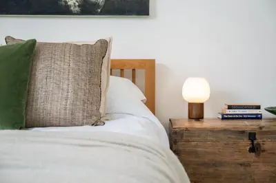 a bed with a pillow and a lamp on a night stand at Beautiful Perranporth country house near the beach in Perranzabuloe