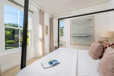 a bedroom with a white bed with a book on it at Beautiful Perranporth country house near the beach in Perranzabuloe