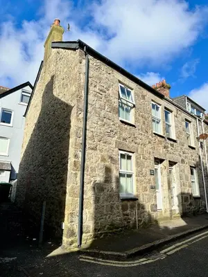an old stone building with a shadow on the side of it at Kerris Cottage in St Ives