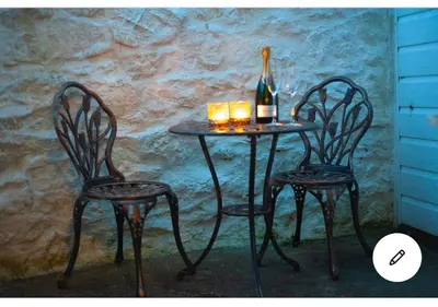 a table with two chairs and a bottle of wine at Kerris Cottage in St Ives