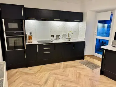 a kitchen with black cabinets and a wooden floor at Kerris Cottage in St Ives