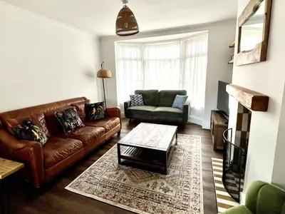 a living room with a leather couch and a chair at 3-Bedroom Holiday Home, Newquay with Garden & Parking - 150 Steps to the Beach! in Newquay