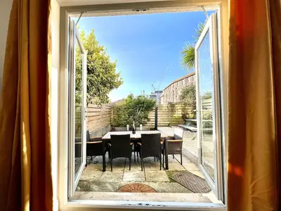 a view of a table and chairs from a window at 3-Bedroom Holiday Home, Newquay with Garden & Parking - 150 Steps to the Beach! in Newquay