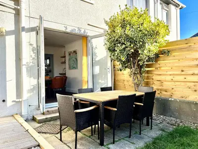 a wooden table and chairs on a patio at 3-Bedroom Holiday Home, Newquay with Garden & Parking - 150 Steps to the Beach! in Newquay