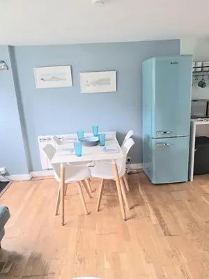 a dining room with a table and a refrigerator at Ocean Blue in Saint Martin