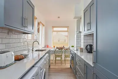 a kitchen with gray cabinets and a table with chairs at Finest Retreats - Templemore in Widemouth Bay