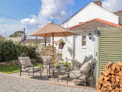 a patio with a table and chairs and an umbrella at Trewenna in Tregoney