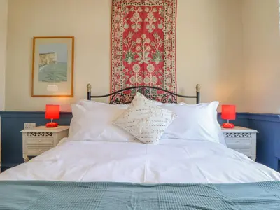 a bedroom with a bed with two lamps and a rug at Trewenna in Tregoney