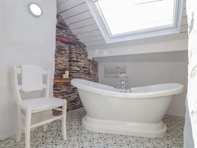 a white bath tub in a bathroom with a skylight at Trewenna in Tregoney