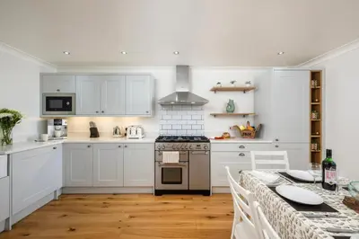 a white kitchen with a table and a stove at Treallen Rock in Saint Minver