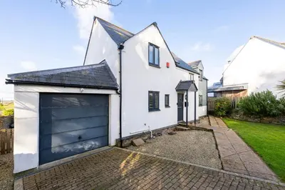 a white house with a large garage at Treallen Rock in Saint Minver