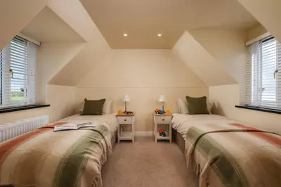 two beds in a room with two windows at Treallen Rock in Saint Minver