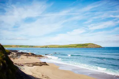 a beach with a small island in the water at St Moritz Hotel and Cowshed Spa in Polzeath