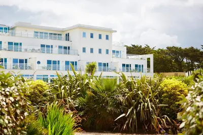 a white building with blue windows and plants at St Moritz Hotel and Cowshed Spa in Polzeath