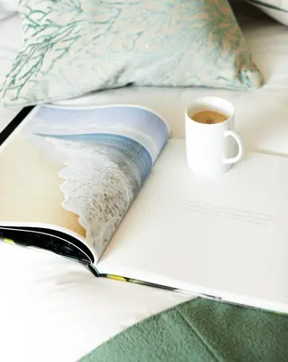 an open book with a cup of coffee on a bed at St Moritz Hotel and Cowshed Spa in Polzeath