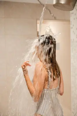 a woman is spraying herself with water at St Moritz Hotel and Cowshed Spa in Polzeath