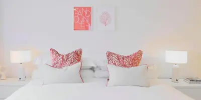 a white bedroom with a white bed with red and white pillows at St Moritz Hotel and Cowshed Spa in Polzeath