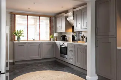 a kitchen with white cabinets and a large window at Easy Oars - Flushing, Falmouth in Flushing