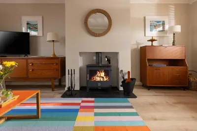 a living room with a fireplace and a television at Easy Oars - Flushing, Falmouth in Flushing
