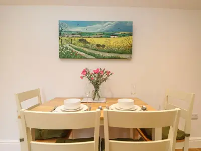a dining room table with chairs and a painting on the wall at Little Tregarrick in Helston