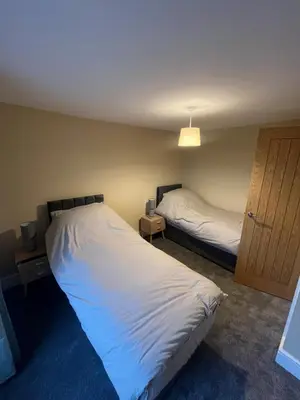 a bedroom with two beds and a light fixture at Cosy Cottage Hot Tub Sleeps 8 Log Fires in Carnbrea