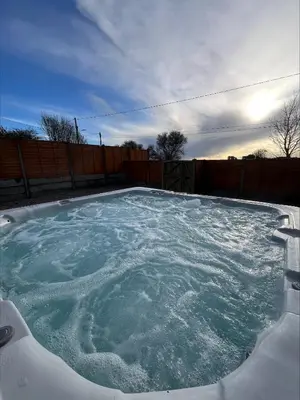 a hot tub filled with water in a backyard at Cosy Cottage Hot Tub Sleeps 8 Log Fires in Carnbrea
