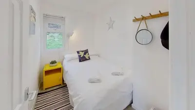 a small bedroom with a white bed and a yellow table at D05 Cedrica, Riviere Towans in Hayle