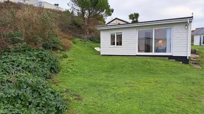 a small white house on a grassy yard at D05 Cedrica, Riviere Towans in Hayle