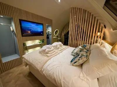 a bedroom with a bed with a tv on the wall at The Secret Garden Glamping Cornwall in Cury