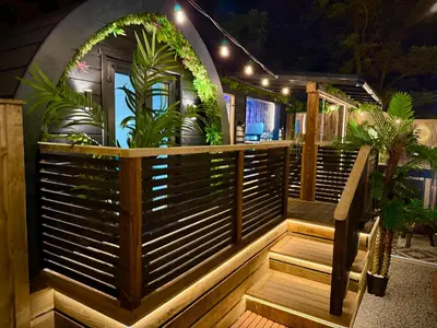 a wooden deck with plants on it at night at The Secret Garden Glamping Cornwall in Cury